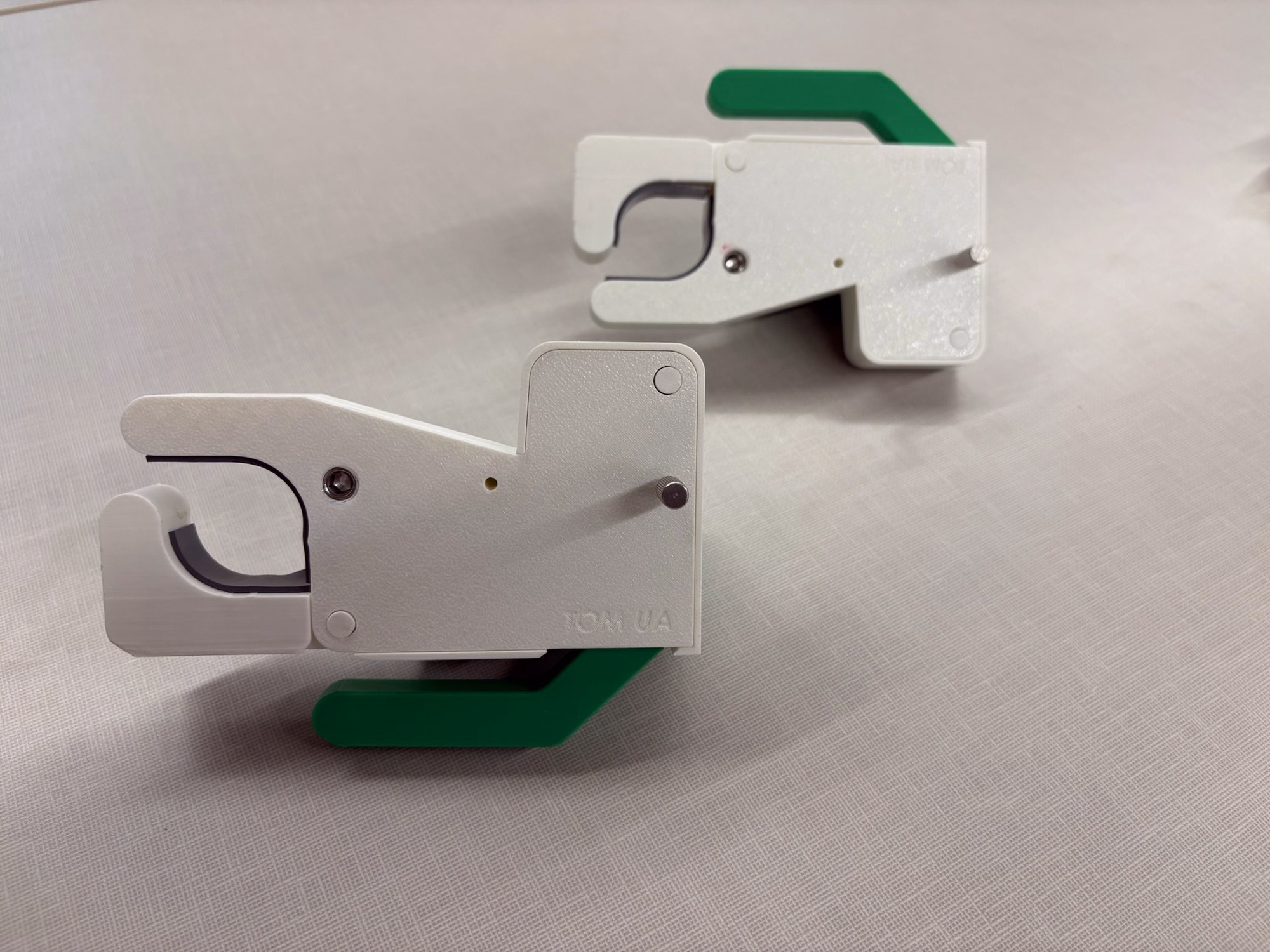 Two assembled white-and-green QuickClamp physical prototypes